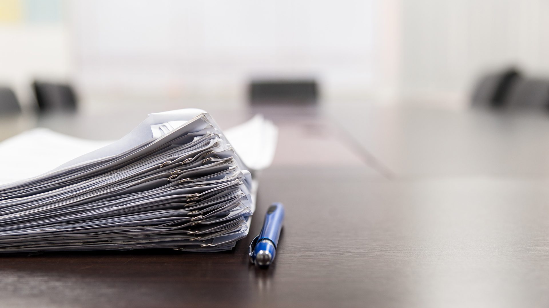 Pile of documents and blue pen on the meeting table with blurred background. Conceptual job interview.; Shutterstock ID 608600555; PO: Mariela; Job: StreetEasy Blog